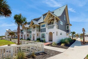 A multi-story residential building with a prominent gable roof, a balcony, and a well-maintained lawn. - Sabal By The Sea | Gulf Views | Steps to Beach (Port Aransas)