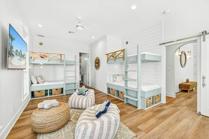 A child's bedroom with bunk beds, a television, and a decorative wall. - Salt and Serenity | Steps to Beach | Game Room (Port Aransas)