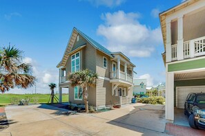 A two-story house with a balcony, a garage, and a well-maintained lawn. - Sandy Fairway | Golf Views | Steps to Beach (Port Aransas)