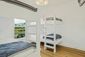 Ein Schlafzimmer mit einem Etagenbett, einem Fenster mit Blick auf Häuser und einem Holzboden.