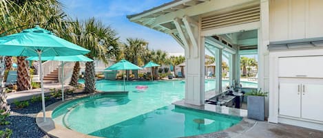 Un área de piscina con piscina circular, sillas de descanso y sombrillas.