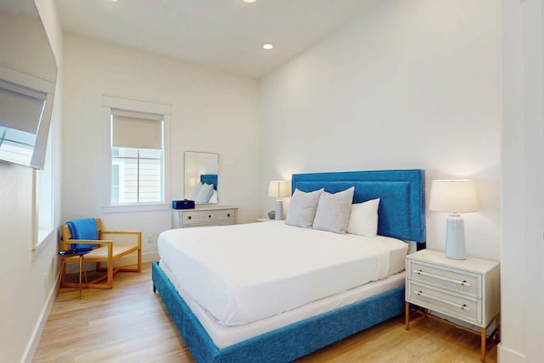 A modern bedroom with a large bed, bedside tables, a chair, and a window. - Songbird | Gulf Views | Private Elevator (Port Aransas)