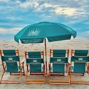 A row of beach chairs with umbrellas at Palmilla Beach Resort & Golf Community. - Sunset On The 9th | Golf Views | Steps to Beach (Port Aransas)