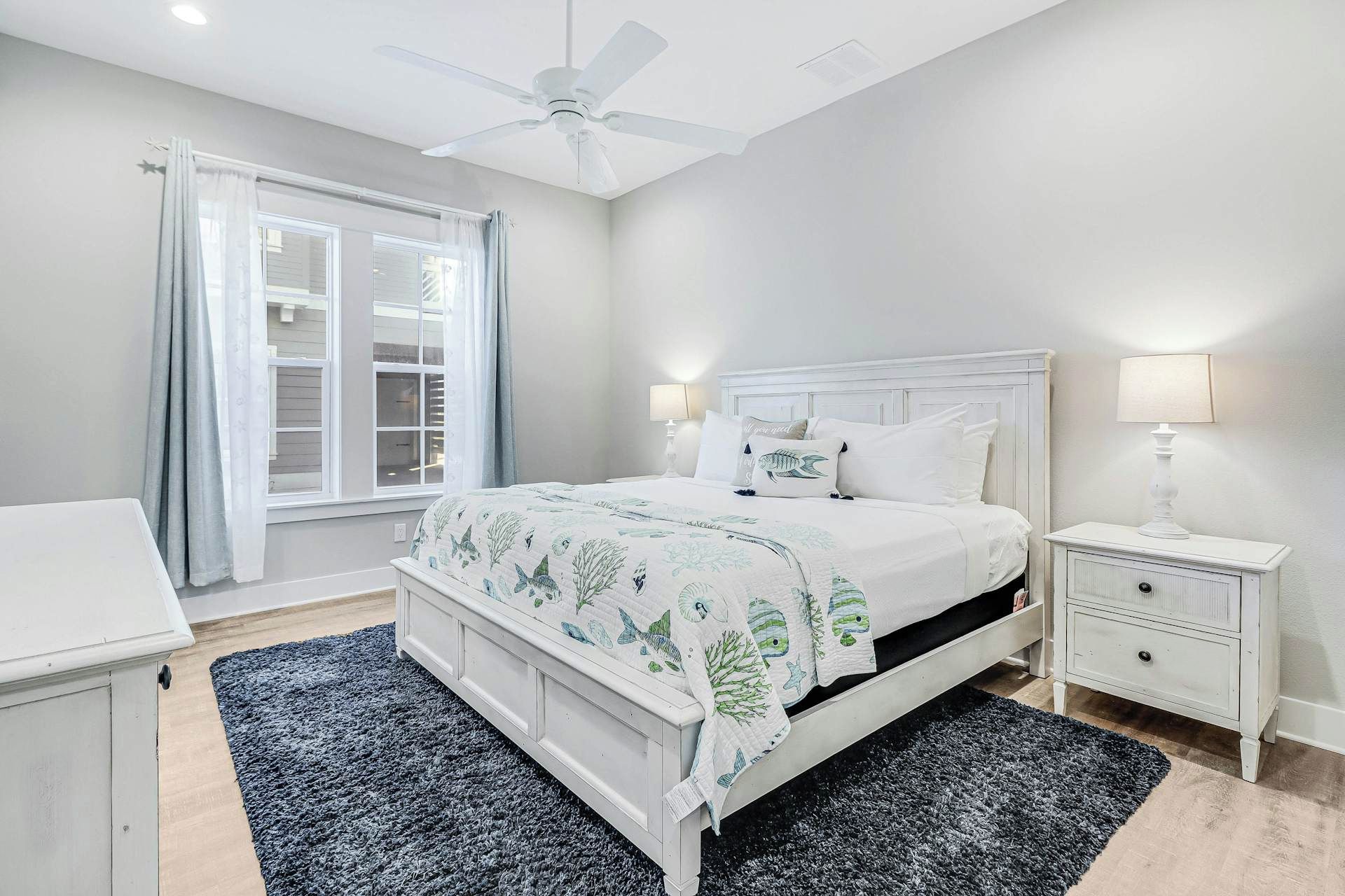 A bedroom with a bed, nightstand, lamp, and a ceiling fan.