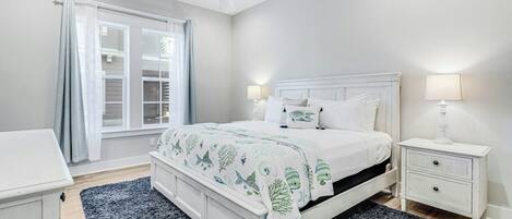A bedroom with a bed, nightstand, lamp, and a ceiling fan.