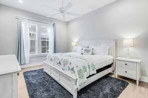 Ein Schlafzimmer mit einem Bett, einem Nachttisch, einer Lampe und einem Deckenventilator.
