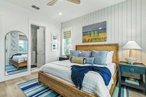 Quarto com cama grande, duas mesas de cabeceira, um espelho e vista para o exterior.