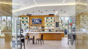 Zona de bar con mostrador de madera, estantes llenos de botellas y una pantalla de televisión.