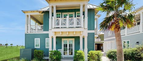 Une maison à deux étages dotée d’un balcon, d’un porche et d’un jardin bien entretenu.