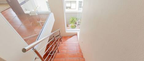 A staircase with metal railings and terracotta tiles.
