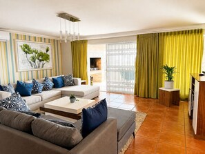 Ein modernes Wohnzimmer mit einem Ecksofa, einem Couchtisch und einer Topfpflanze.