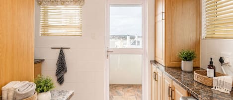 A kitchen with wooden cabinets, a granite countertop, a dishwashing area, and a view through a door.