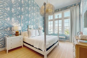Ein Schlafzimmer mit einem Bett, Nachttischen, einer Lampe, einem Fenster mit Vorhängen und Aussicht.