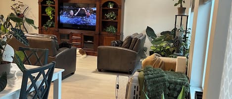 Una sala de estar con televisor, zona de estar y varias plantas.