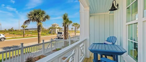 A balcony with a white railing, a table, and two chairs.