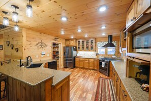 A spacious kitchen with wooden cabinets, granite countertops, and a large island. - Trail, 4BR, 2 King suites, Hot Tub, Pool Table & Firepit (Cherry Log)