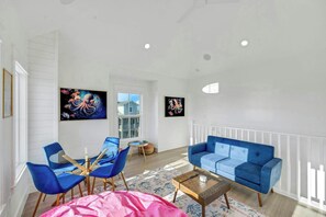 A modern living room with a blue sofa, matching chairs, and a coffee table. - Sip Sip Hooray | Steps to Beach | Resort Amenities (Port Aransas)