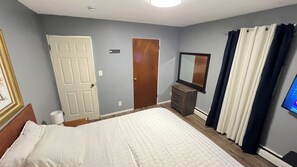 A bedroom with a bed, a dresser, a mirror, and a door. - Charming 2-bedroom apartment with AC in beautiful Fargo (Fargo)