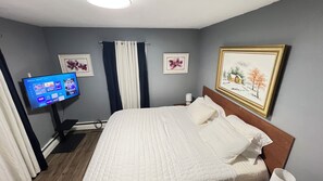 A hotel room with a bed, a TV on a stand, and two framed pictures on the wall. - Charming 2-bedroom apartment with AC in beautiful Fargo (Fargo)