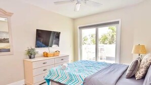 Een slaapkamer met een bed, een televisie, een dressoir en een raam.