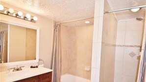 Een badkamer met een wastafel, een bad en een douchehoek.