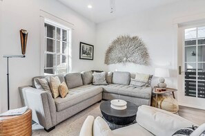 A modern living room with a grey sectional sofa, a round coffee table, and a decorative wall piece. - Real Good Tan | Golf Views | Steps to Beach (Port Aransas)