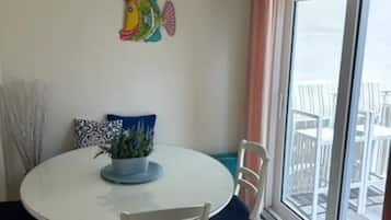 Ein Essbereich mit einem runden Tisch, Stühlen, einem Deckenventilator und Blick durch ein großes Fenster.