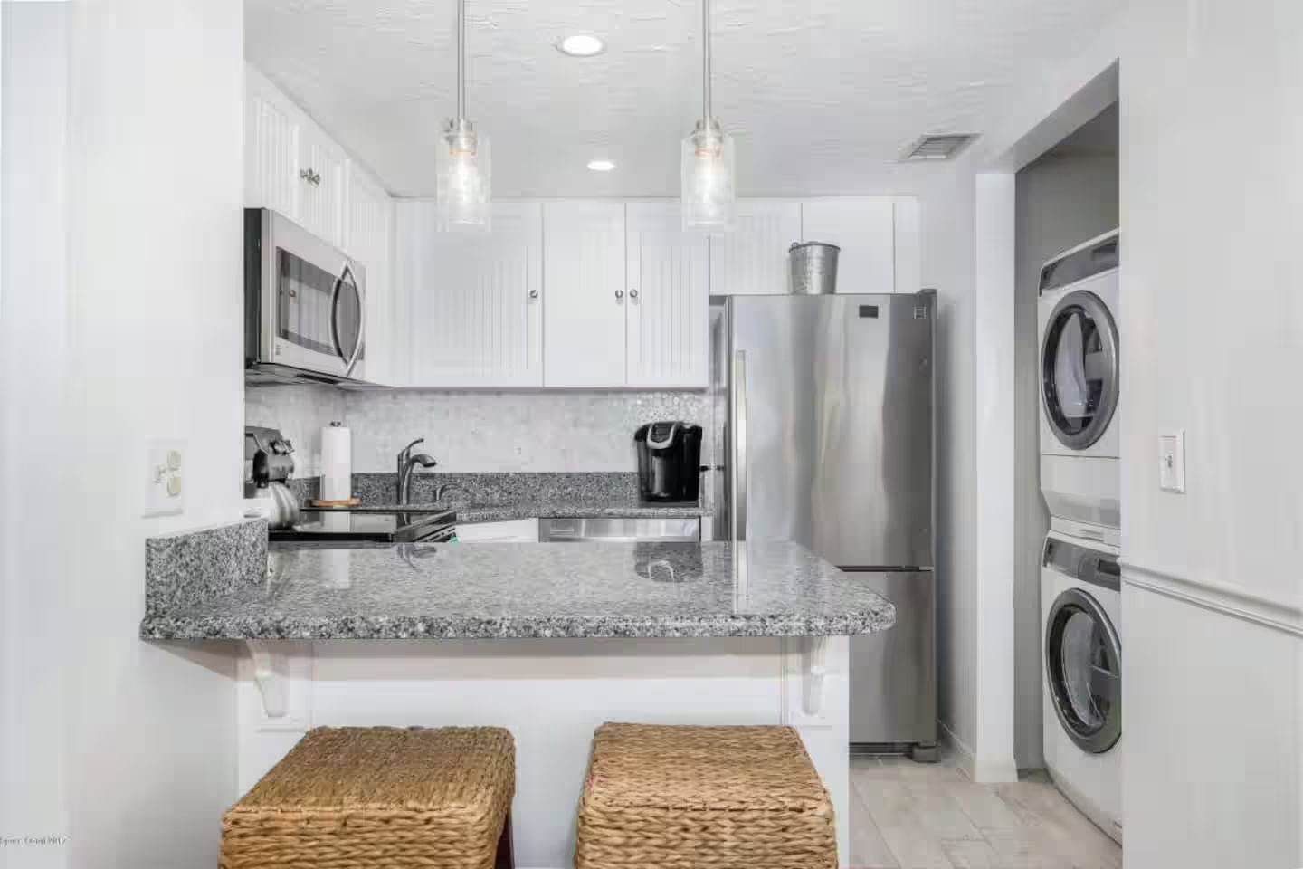 A kitchen with granite countertops, stainless steel appliances, and a built-in washer and dryer.