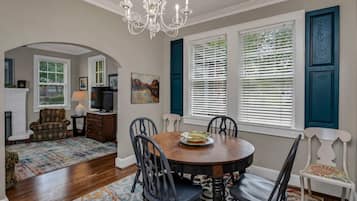 A dining area with a round table, chairs, a chandelier, and a fireplace.