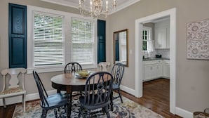 A dining area with a round table, chairs, a chandelier, and a view into the kitchen. - WECO Getaway | Near USC + Downtown (West Columbia)