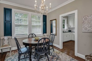 A dining area with a round table, chairs, a chandelier, and a view into the kitchen. - WECO Getaway | Near USC + Downtown (West Columbia)