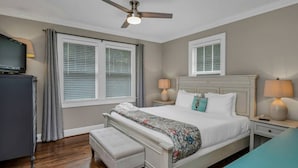 A bedroom with a bed, bedside lamps, a ceiling fan, a television, and a window with blinds. - WECO Getaway | Near USC + Downtown (West Columbia)