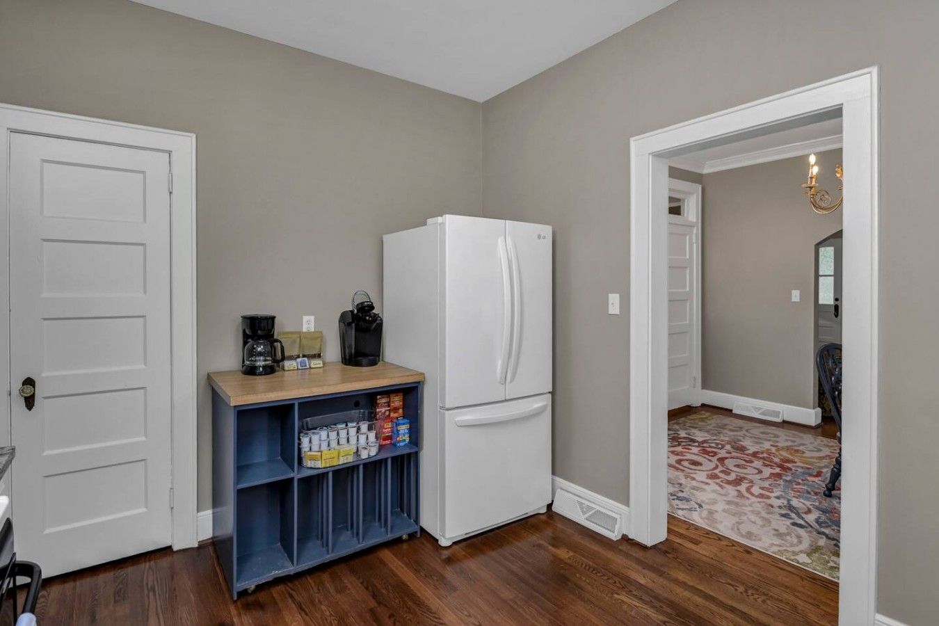A compact kitchenette with a white refrigerator, a coffee maker, and a shelf with various containers.