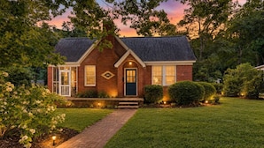 A brick house with a front porch, a well-maintained lawn, and a pathway leading to the entrance. - WECO Getaway | Near USC + Downtown (West Columbia)