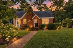 A brick house with a front porch, a well-maintained lawn, and a pathway leading to the entrance. - WECO Getaway | Near USC + Downtown (West Columbia)