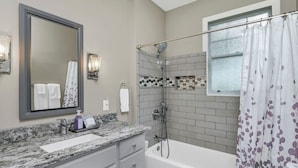 A bathroom with a shower, a bathtub, a vanity with a mirror, and a towel rack. - WECO Getaway | Near USC + Downtown (West Columbia)