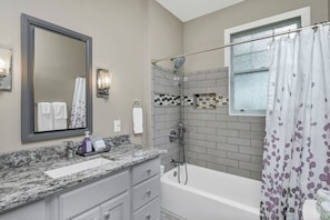 A bathroom with a shower, a bathtub, a vanity with a mirror, and a towel rack. - WECO Getaway | Near USC + Downtown (West Columbia)