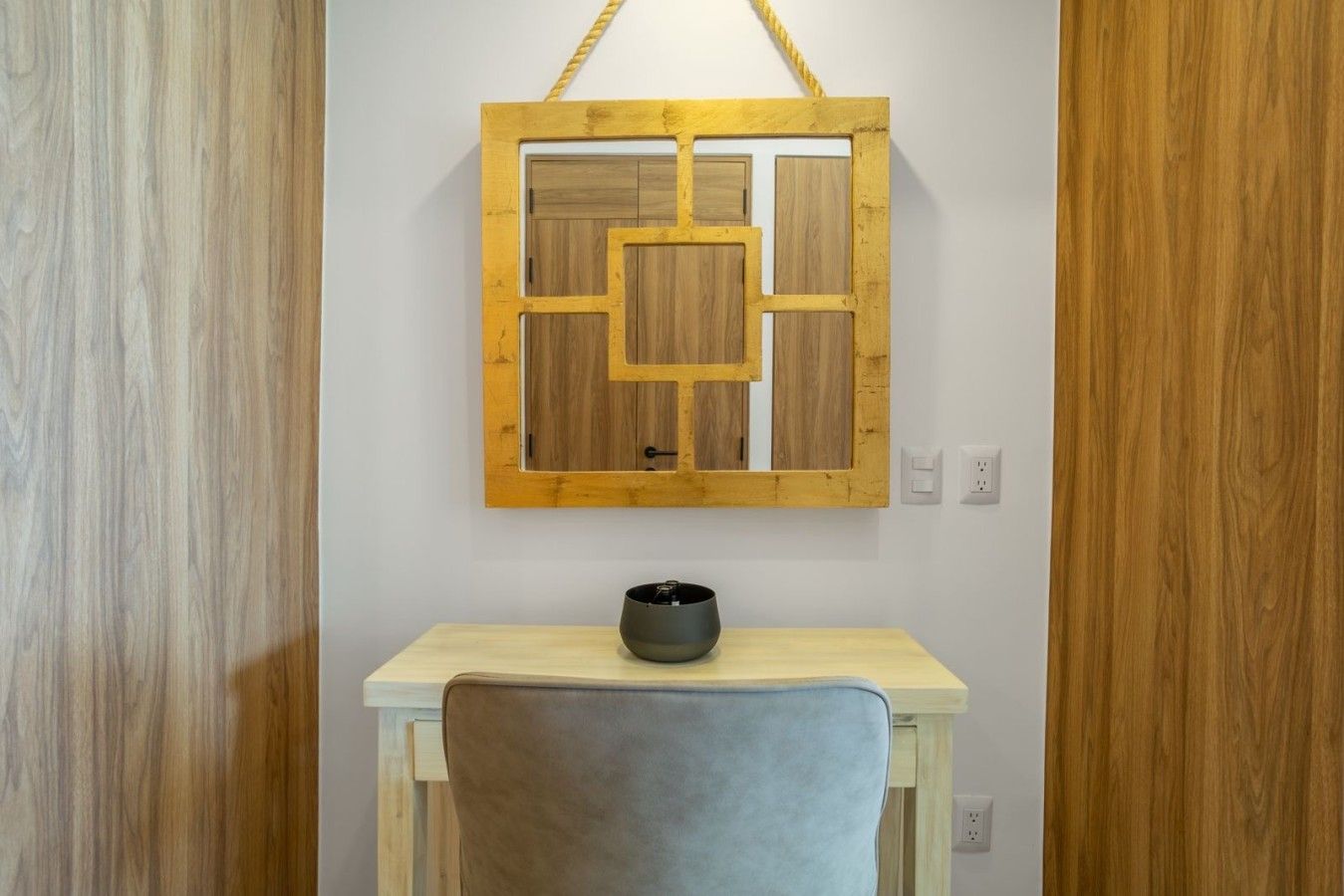 A room with a wooden wall panel, a light-colored desk, and a chair.
