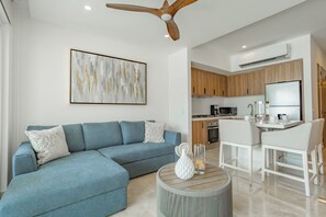 Ein modernes Wohnzimmer mit einem Ecksofa, einem runden Couchtisch und einem Deckenventilator.