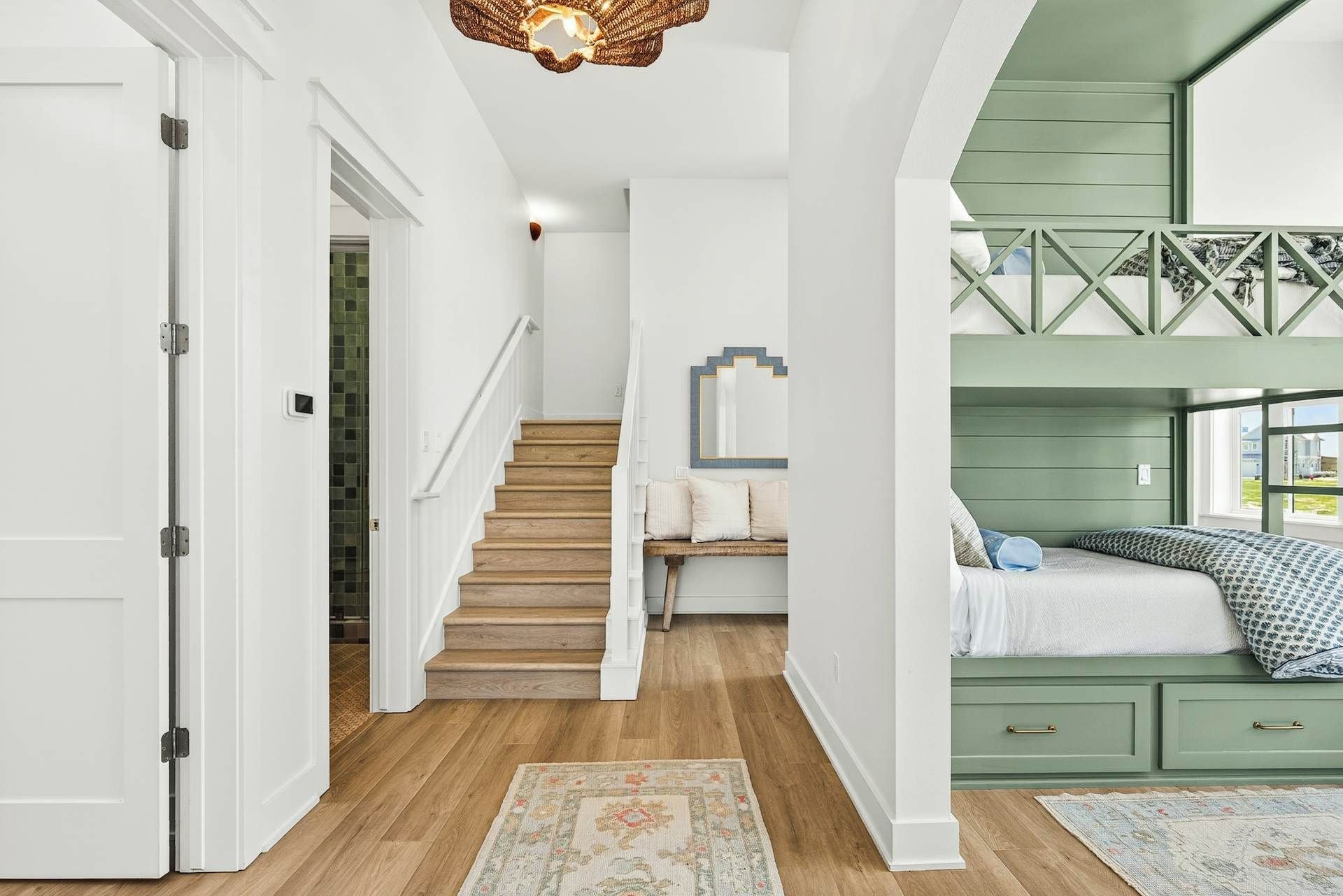 A staircase leading to a bedroom with a bunk bed, a small seating area, and a decorative mirror.