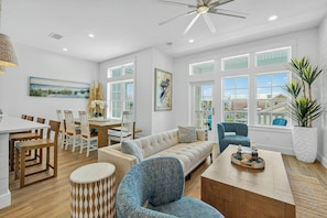A spacious living area with a dining table, chairs, a sofa, and a coffee table. - Sunset Shores Escape| Water Views | Steps to Beach (Port Aransas)