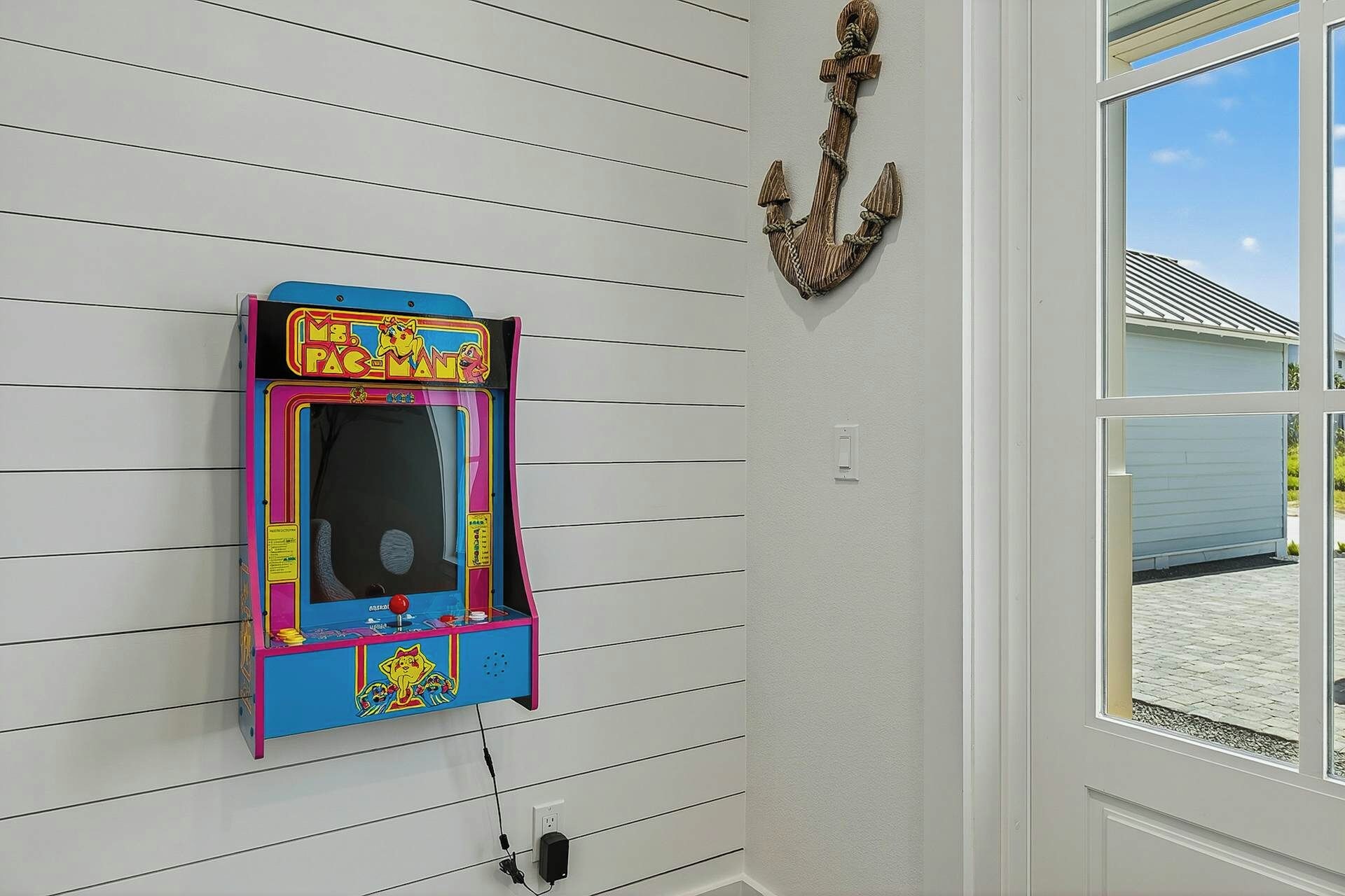 Máquina de arcade Pac-Man fixada na parede, com uma janela ao lado direito.
