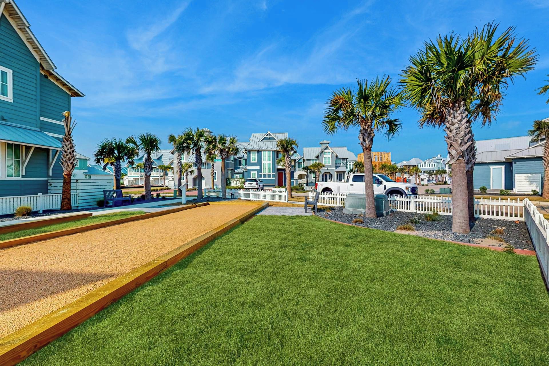 A residential area with houses, a lawn, and a gravel path.
