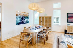 Een eethoek met een houten tafel en stoelen, een groot schilderij en een kast met glazen deuren.