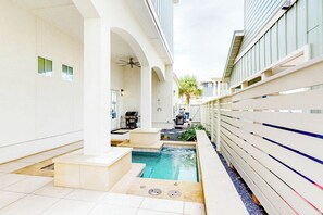 Een zwembadgedeelte met een jacuzzi, een barbecue en een kleine tuin.