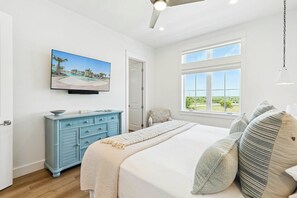 Ein Schlafzimmer mit einem Bett, einem Schminktisch, einem an der Wand befestigten Fernseher und einem Fenster mit Blick.
