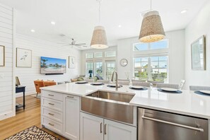 Une cuisine moderne avec des meubles blancs, des appareils en acier inoxydable et un grand îlot central doté d’un évier.
