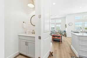 Une cuisine moderne avec des meubles blancs, un îlot central et une vue sur l’extérieur.