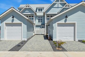 Ein zweistöckiges Haus mit Garageneinfahrt, Auffahrt und einem kleinen Garten.