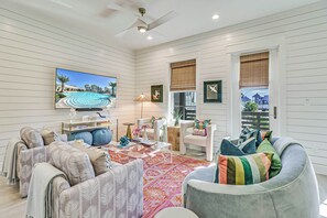 A spacious living room with a large flat-screen TV, comfortable seating, and a view of the outdoors. - The Palm | Steps to Beach | Resort Amenities (Port Aransas)